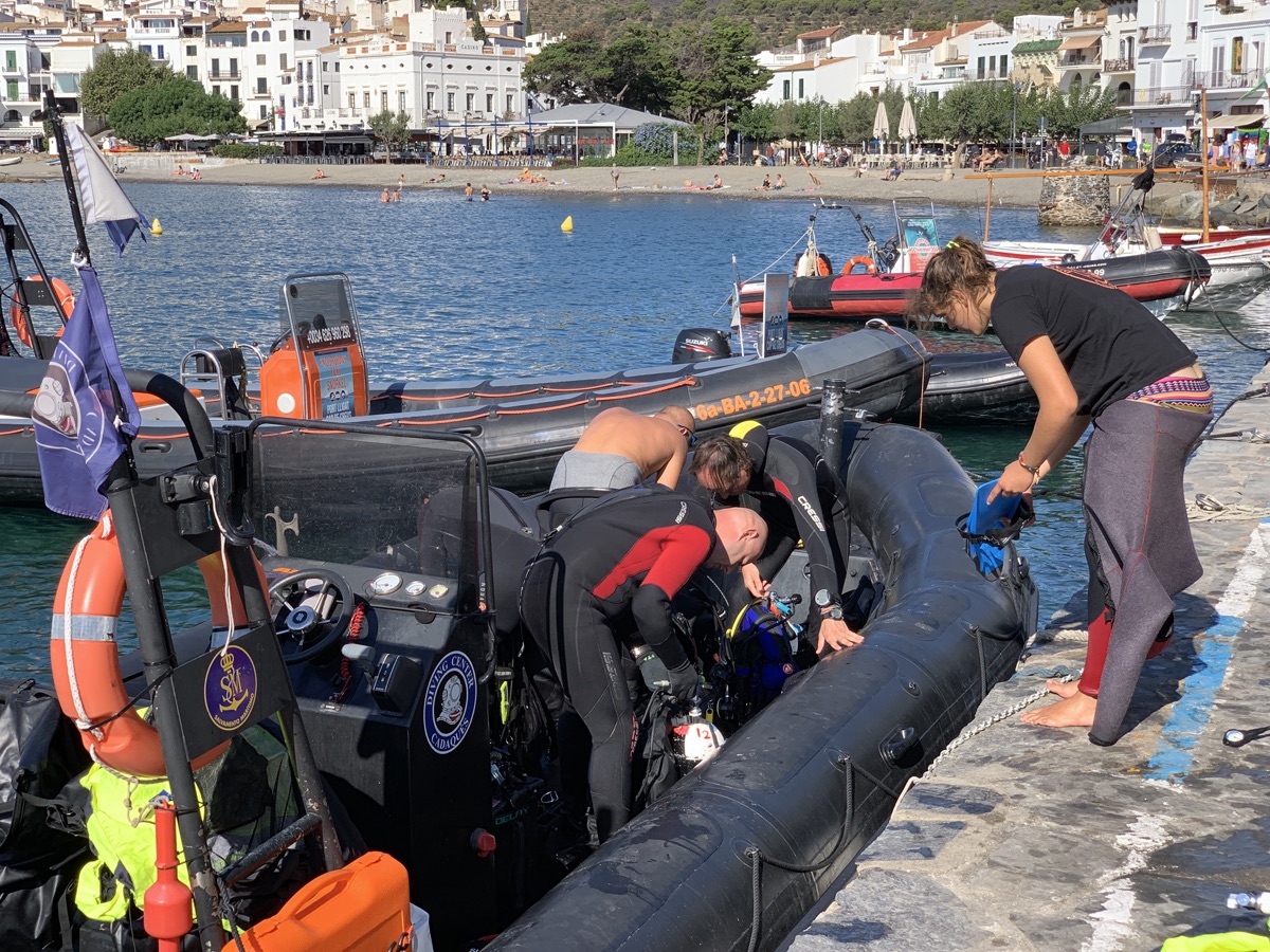 Divers preparing gear beside a rigid inflatable dive boat